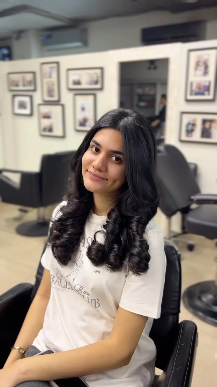 Shoulder-length hair blow-dried into full, glossy curls